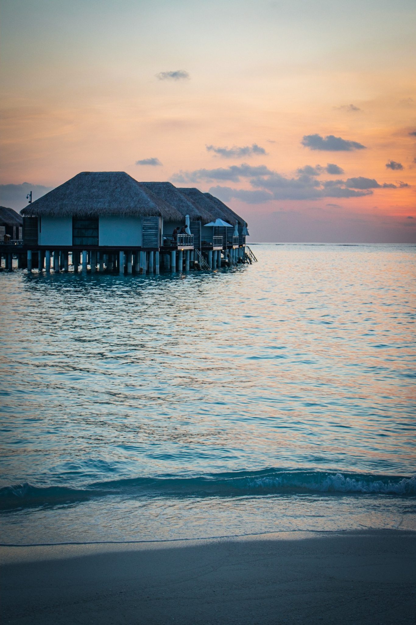 View of the overwater bungalows at sunset in The Maldives