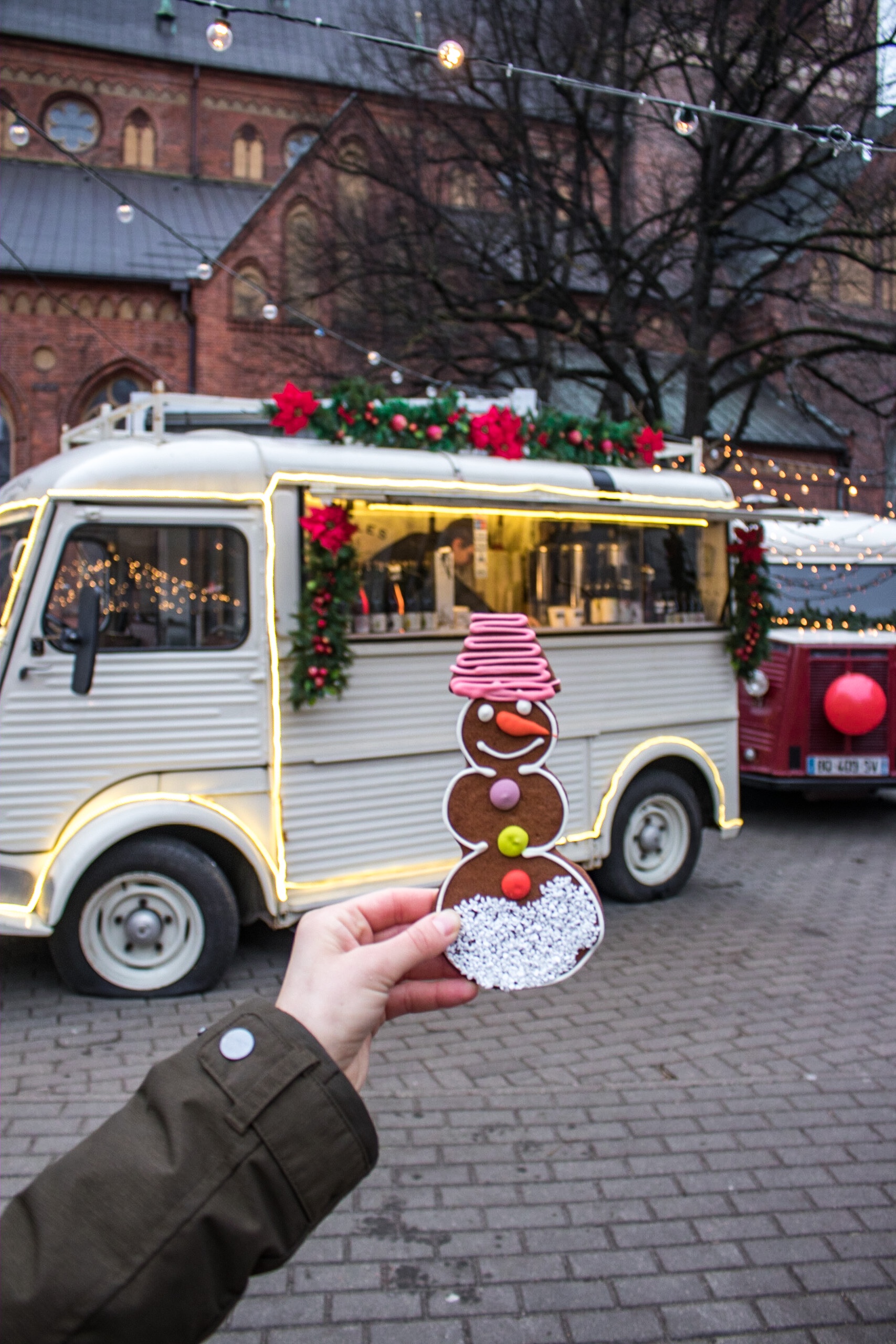 Holding a gingerbread cookie in front of the Christmas Market in Riga, Latvia